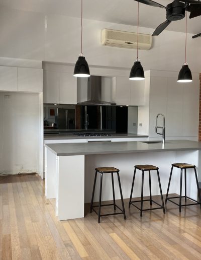 A modern kitchen featuring a white island and warm wooden floors, creating a bright and inviting atmosphere.