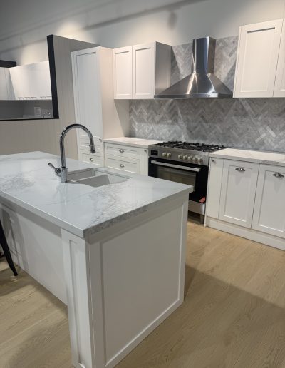 A modern kitchen featuring white cabinets and a sleek marble island, creating a bright and elegant cooking space.