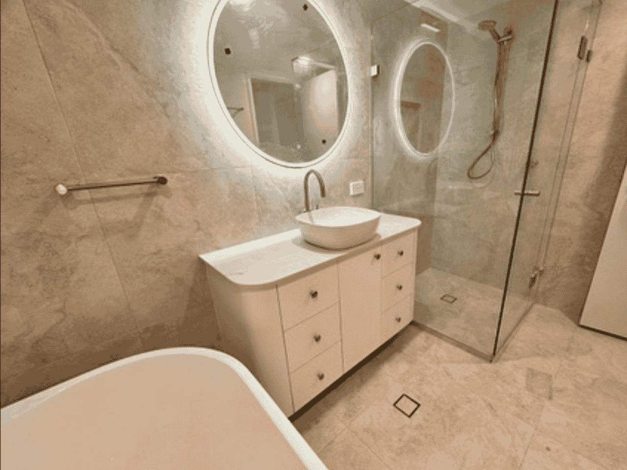 A bathroom featuring a sink, shower, and mirror, showcasing a clean and modern design.